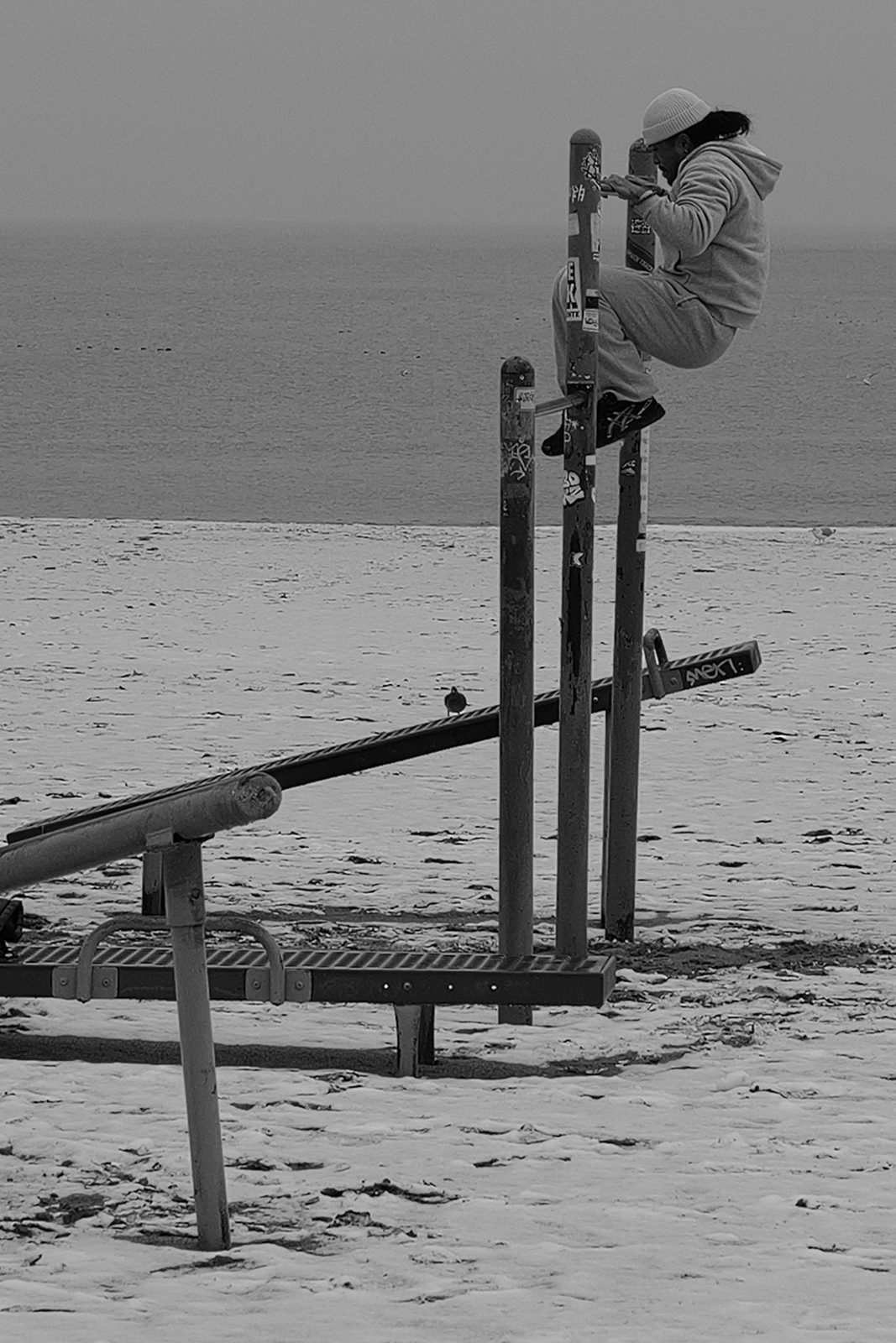 Homme faisant des tractions sur des barres de sport face a la mer, Coney Island