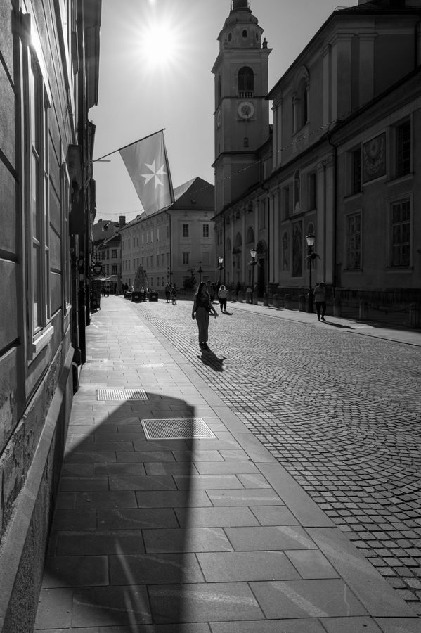 Passant traversant une ruelle ensoleillee pres d'un chateau, Ljubljana